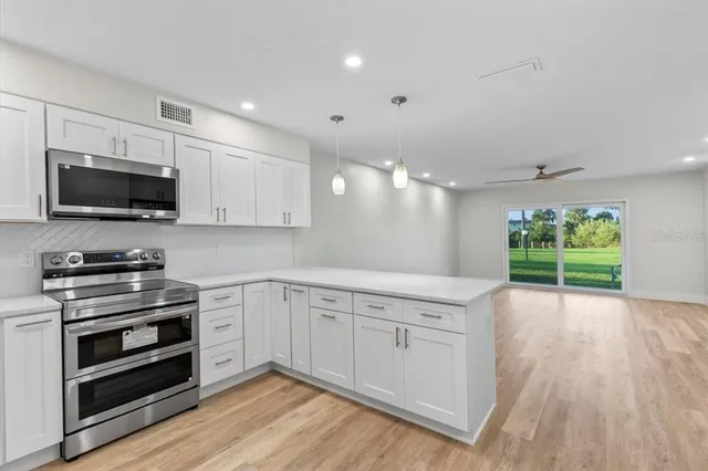 a large kitchen with stainless steel appliances a refrigerator and a wooden floor
