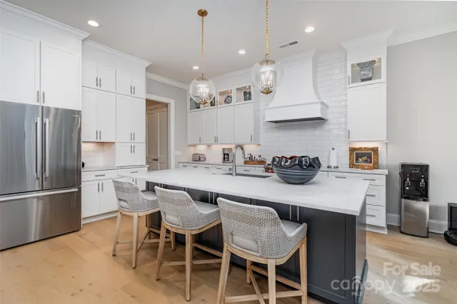 a kitchen with stainless steel appliances granite countertop a sink a stove a refrigerator and chairs