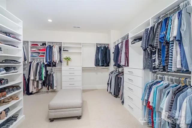 a walk in closet with clothes and shoes