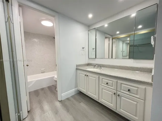 a bathroom with a granite countertop sink mirror and bathtub
