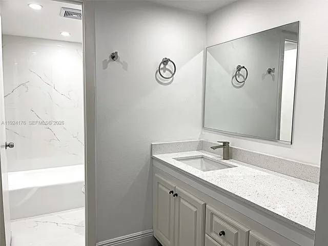 a bathroom with a granite countertop sink and a mirror