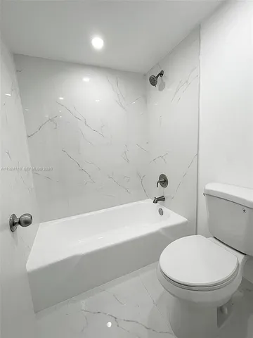 a bathroom with a white toilet sitting next to a bathtub