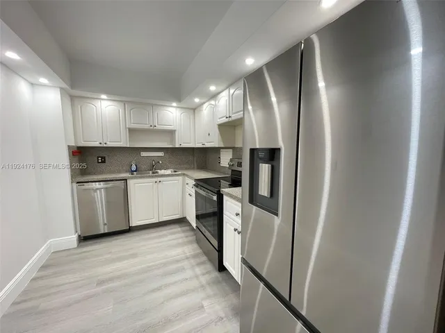 a kitchen with white cabinets and stainless steel appliances