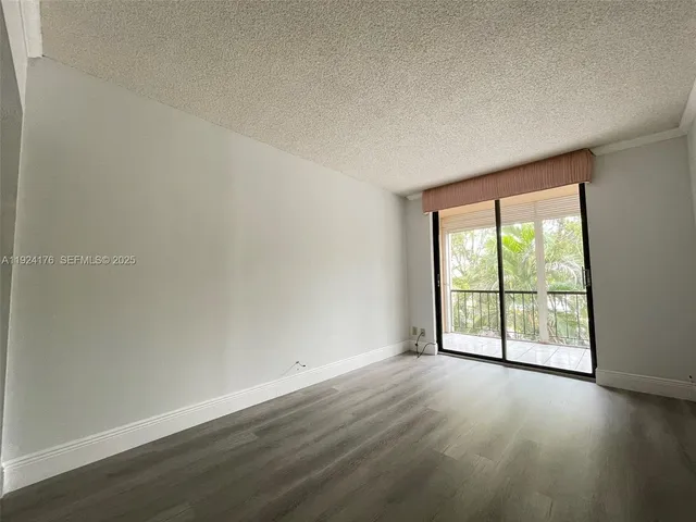 an empty room with wooden floor and windows with curtains view