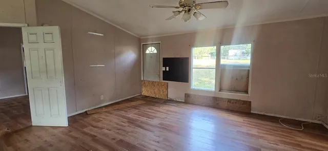 an empty room with wooden floor fan and windows