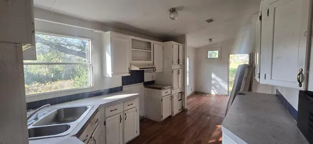 a view of a kitchen with a sink a refrigerator and wooden floor