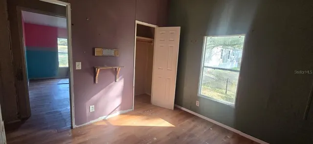 a view of an empty room with window and wooden floor