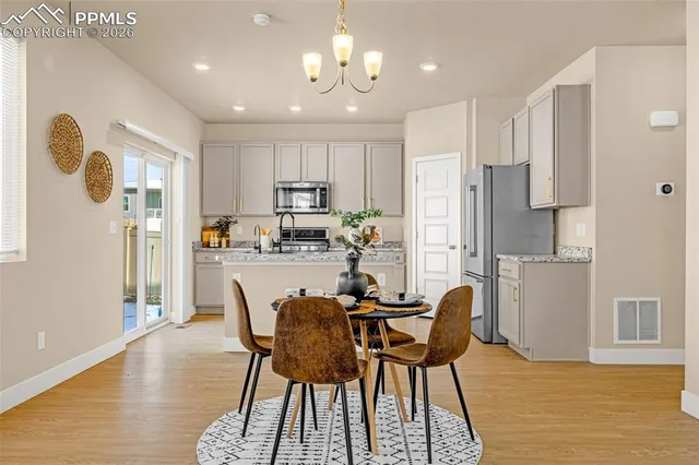 a kitchen with stainless steel appliances granite countertop a dining table chairs refrigerator and microwave