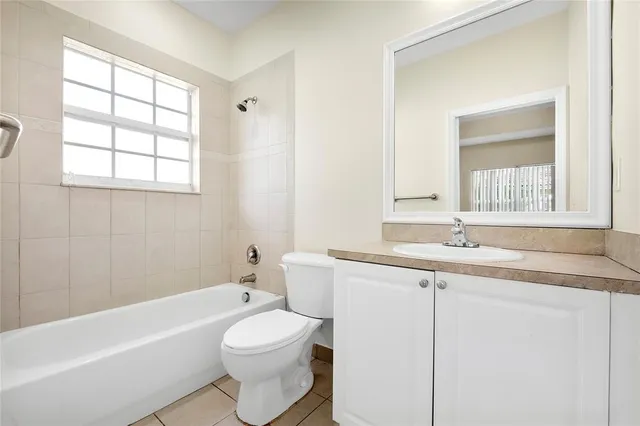 a bathroom with a granite countertop sink toilet a large mirror a bathtub and next to a window