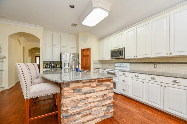 a large white kitchen with kitchen island a sink a stove and refrigerator
