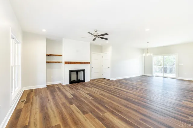 a view of a livingroom with a fireplace a ceiling fan and windows