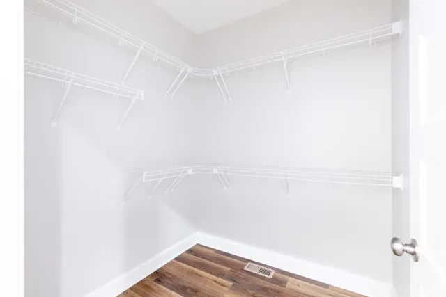 an empty room with wooden floor chandelier fan and windows