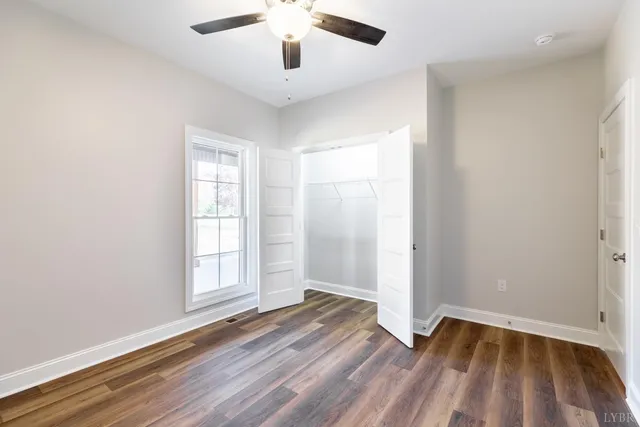 an empty room with a window and a ceiling fan