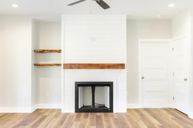 a view of an empty room with wooden floor fireplace and a window