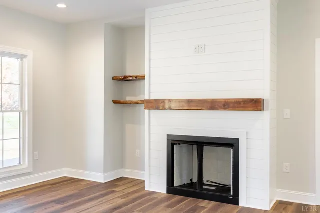 a view of a kitchen and an empty room with wooden floor