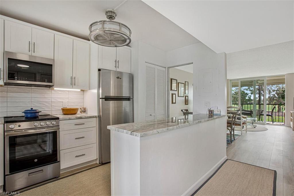 4380 27th Court Southwest, Unit 202 Naples, FL 34116 - Photo 18 of 24 a kitchen with white cabinets and stainless steel appliances