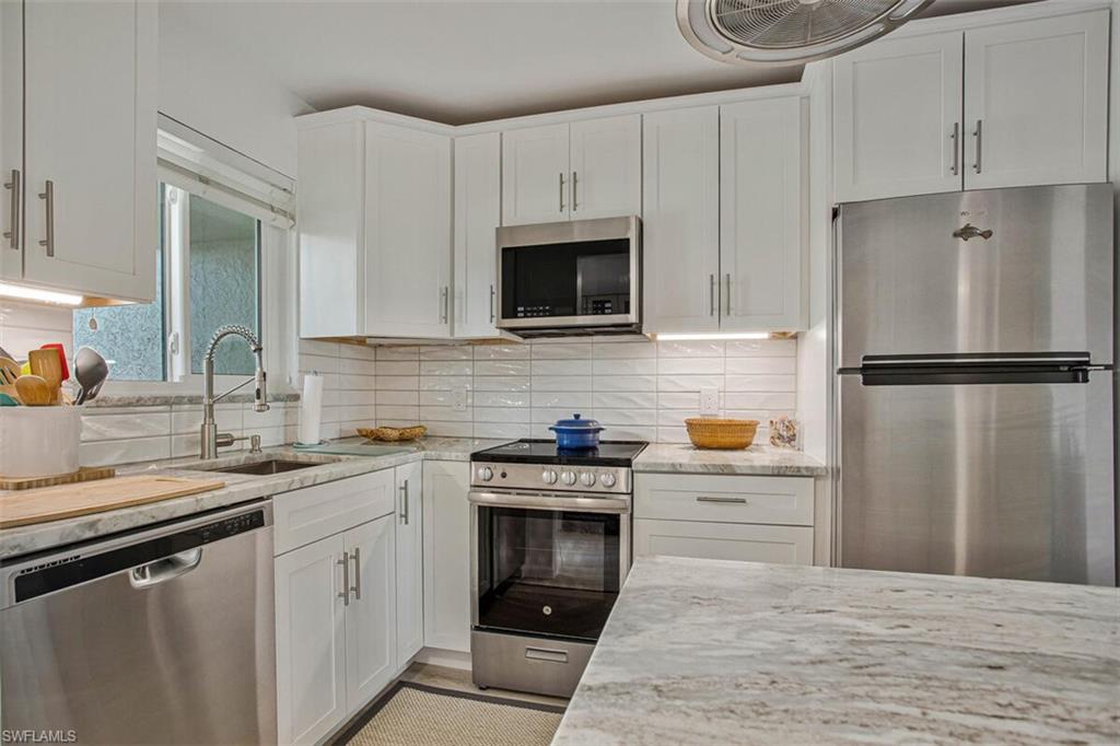 4380 27th Court Southwest, Unit 202 Naples, FL 34116 - Photo 19 of 24 a kitchen with cabinets stainless steel appliances and wooden floor