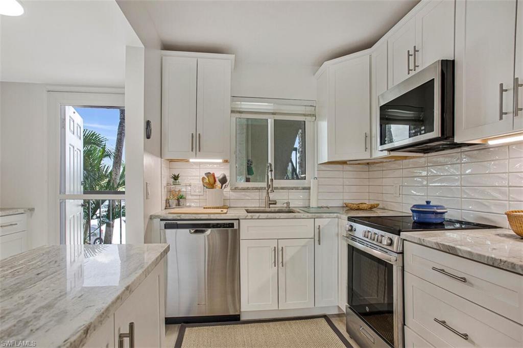 4380 27th Court Southwest, Unit 202 Naples, FL 34116 - Photo 3 of 24 a kitchen with stainless steel appliances granite countertop a sink stove and microwave