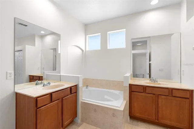 a bathroom with a sink double vanity granite tub shower and a mirror