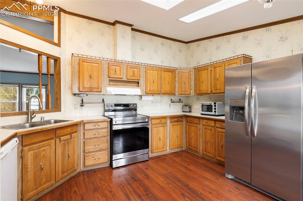 13335 Gymkhana Road Peyton, CO 80831 - Photo 20 of 38 Kitchen featuring wood cabinetry, wood-finish flooring, and a stainless steel appliance suite