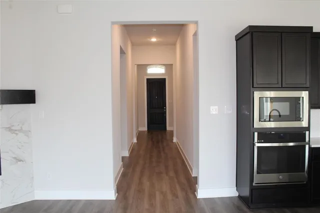a view of a hallway with wooden floor and cabinets