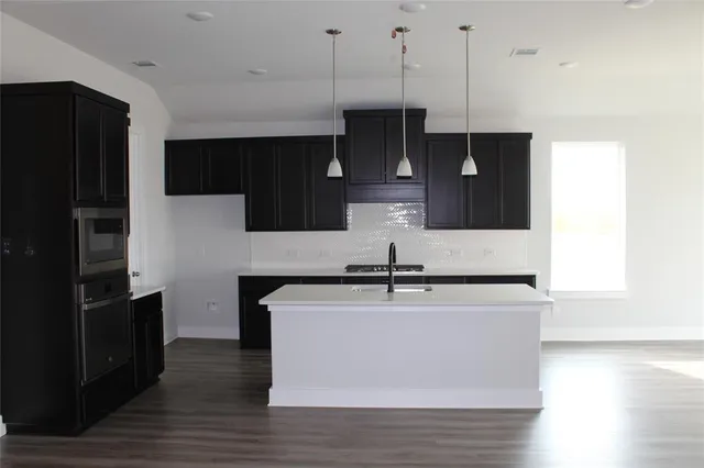 a kitchen with kitchen island stainless steel appliances a sink cabinets and wooden floor