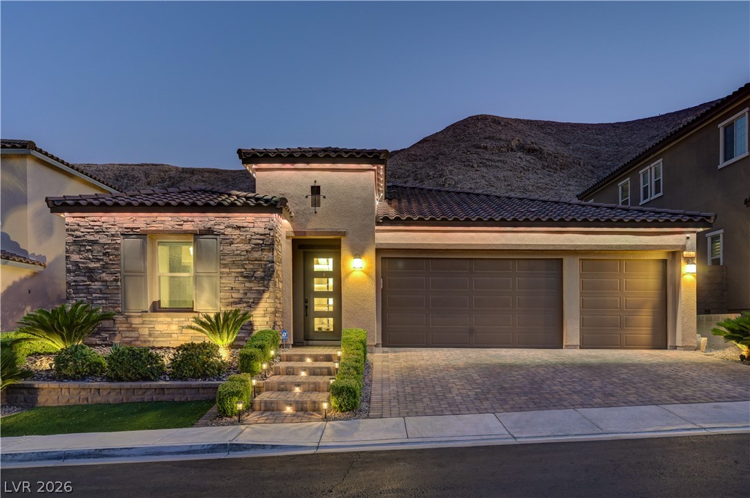 3943 Reyes Avenue Las Vegas, NV 89141 - Photo 81 of 95 Illuminated stone facade and paver driveway lead to a welcoming entry, framed by desert landscaping.