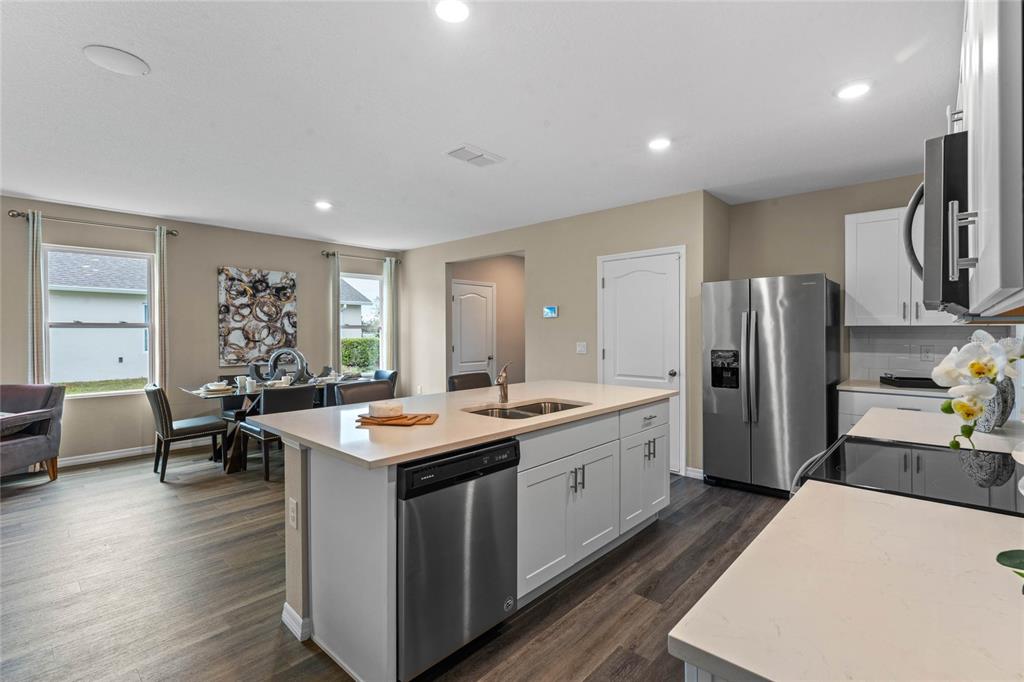 1816 Three Bars Road Kissimmee, FL 34744 - Photo 11 of 59 a kitchen with stainless steel appliances granite countertop a refrigerator a sink dishwasher a dining table and chairs with wooden floor