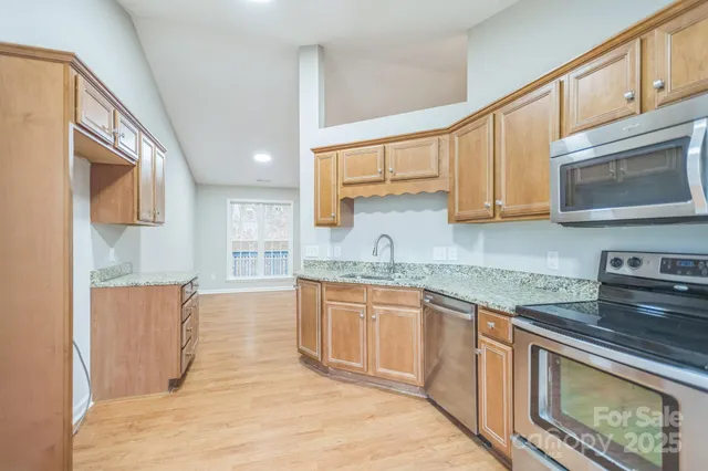 a kitchen with stainless steel appliances granite countertop a stove a sink and a microwave