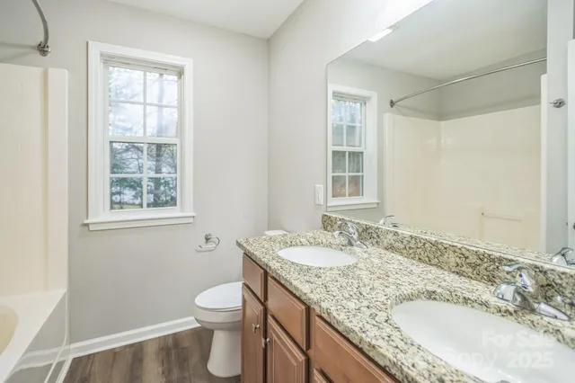a bathroom with a granite countertop sink a toilet and a window