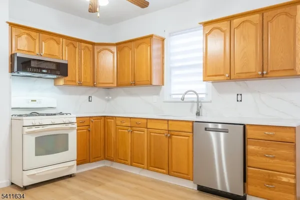 a kitchen with stainless steel appliances granite countertop wooden cabinets a sink and a granite counter tops with a large window