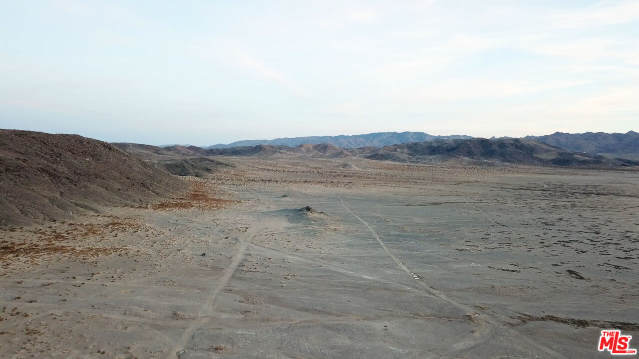 a view of a dry field with mountains in the background