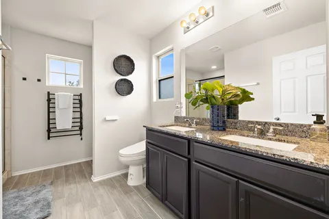 a bathroom with a granite countertop toilet sink and mirror
