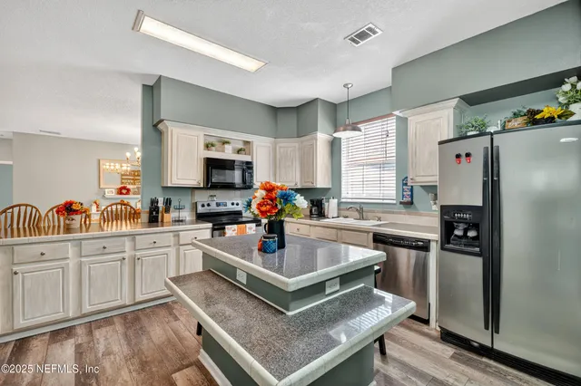 a kitchen with stainless steel appliances granite countertop a refrigerator stove microwave and sink