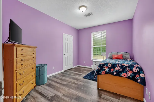 a bedroom with a bed and a flat tv screen on dresser