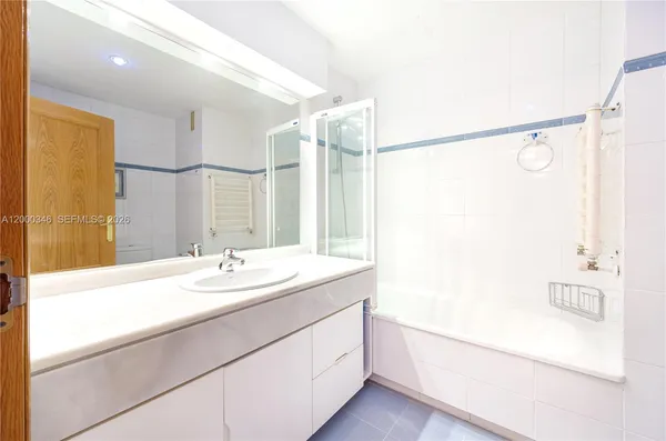 a bathroom with a granite countertop sink a mirror a shower and a bathtub