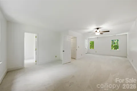 an empty room with a chandelier fan and windows