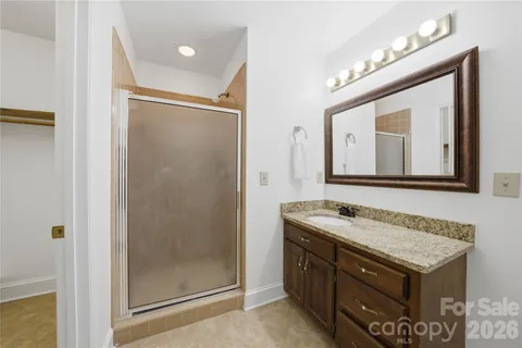a bathroom with a granite countertop sink a mirror and a shower