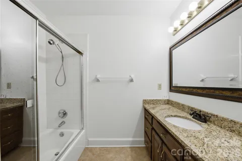 a bathroom with a granite countertop sink a mirror and shower