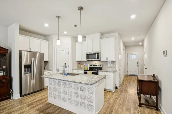 a kitchen with stainless steel appliances a stove a sink a refrigerator a center island and furniture