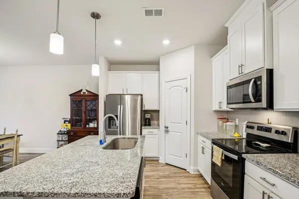 a kitchen with stainless steel appliances granite countertop a refrigerator a stove and a sink