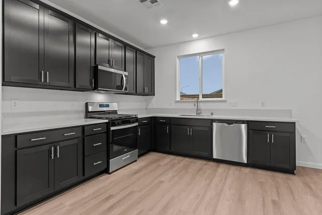 a kitchen with stainless steel appliances granite countertop a sink a stove and cabinets