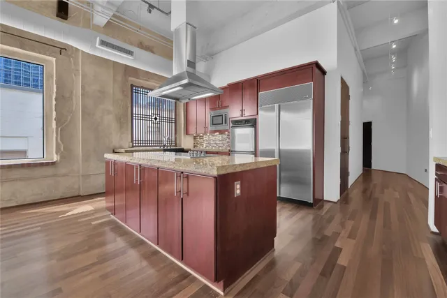 a kitchen with stainless steel appliances granite countertop a refrigerator a sink dishwasher a stove and white countertops with wooden floor