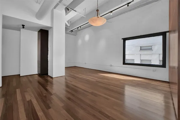 a view of an empty room with wooden floor ceiling fan