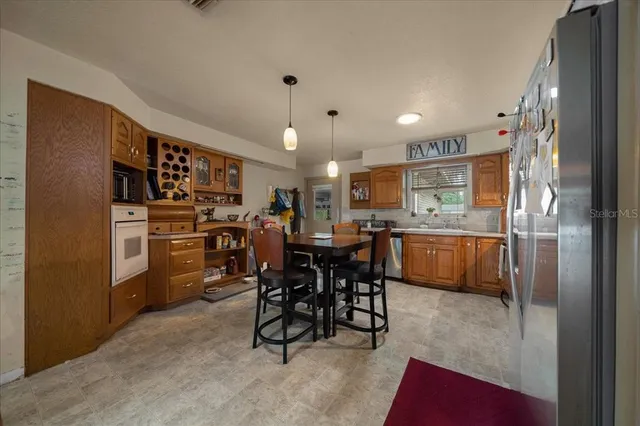 a kitchen with stainless steel appliances kitchen island granite countertop a table chairs sink and cabinets