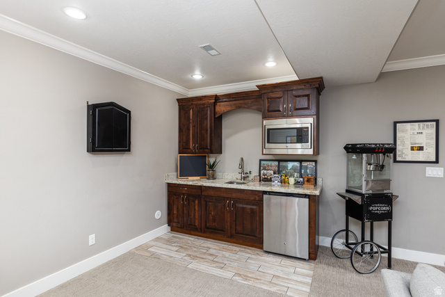 1132 Sunset Dunes Way Draper, UT 84020 - Photo 21 of 35 Built-in wet bar featuring dark wood cabinetry, a stainless steel microwave, and a stainless steel under-counter refrigerator