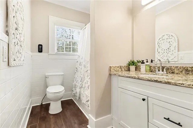 a bathroom with a granite countertop sink a toilet and a window