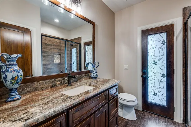 a bathroom with a granite countertop sink a toilet and a mirror