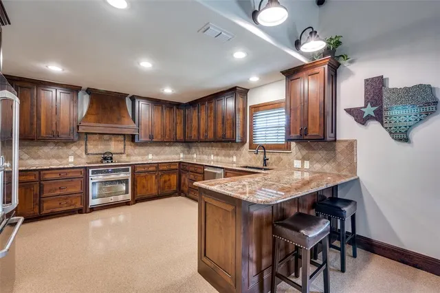 a kitchen with stainless steel appliances granite countertop wooden cabinets a stove top oven a sink and dishwasher