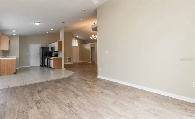 an empty room with a kitchen and stainless steel appliances